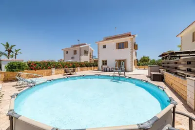 a large swimming pool with a house in the background at Villa Stephanie Oasis in Ayia Napa