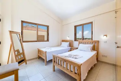 a room with two beds and a chair at Villa Stephanie Oasis in Ayia Napa