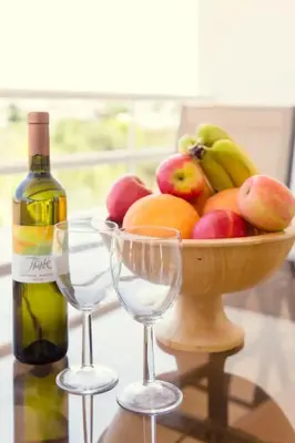 a bowl of fruit with a bottle of wine and two wine glasses at NISSI BEACH Apt 2 RESORT AND SEA VIEW FREE WIFI in Ayia Napa