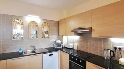 a kitchen with black counter tops and wooden cabinets at NISSI BEACH Apt 2 RESORT AND SEA VIEW FREE WIFI in Ayia Napa