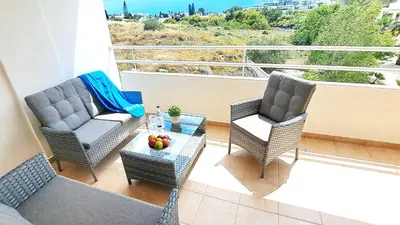 a balcony with two chairs and a table with fruit on it at NISSI BEACH Apt 2 RESORT AND SEA VIEW FREE WIFI in Ayia Napa