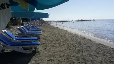 a row of blue lounge chairs on a beach with a pier at Luxurious Orestis in Limassol