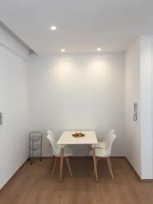 a table and chairs in a room with a white wall at Modern 1 bedroom sea view beach apartment in Limassol
