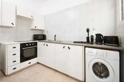 a kitchen with white cabinets and a washer and dryer at Urban Condo 11 - 1 Bdr in Nicosia