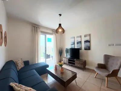 a living room with a blue couch and a tv at Mythical Sands - Aura in Paralimni