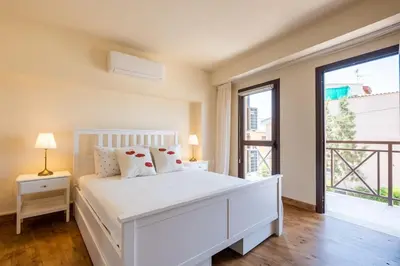 a white bedroom with a bed and a large window at Traditional House Agia Varvara Village in Ayvaryara
