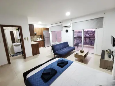 a bedroom with a blue bed and a living room at Must Stay - Finikoudes Studio in Larnaka