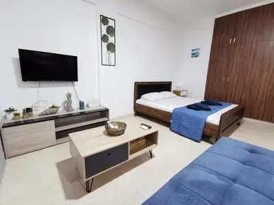 a bedroom with a bed and a tv and a couch at Must Stay - Finikoudes Studio in Larnaka