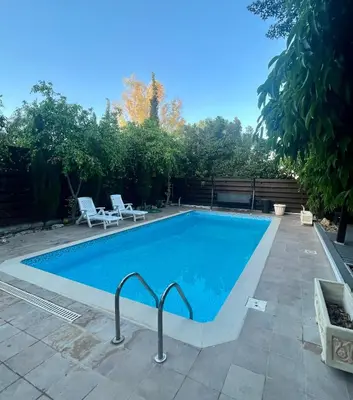a swimming pool in a yard with two chairs at A Detached Floor in Parekklisha