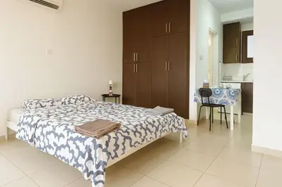 a bedroom with a bed and a table and a kitchen at Old town studio in Limassol