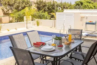 a table with food and fruit on it next to a pool at Protaras Mythical Seas in Protaras