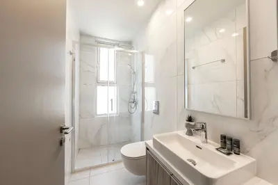 a white bathroom with a shower and a sink at Protaras Mythical Seas in Protaras