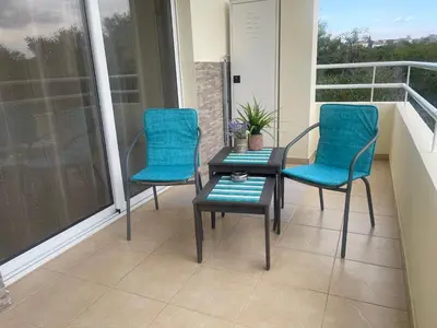 two chairs and a table on a balcony at Nissi Beach beautiful apartment in Ayia Napa
