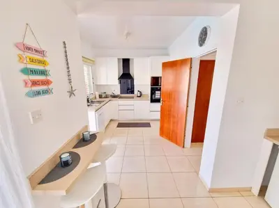 a kitchen with white cabinets and a tile floor at Villa Malama in Paralimni