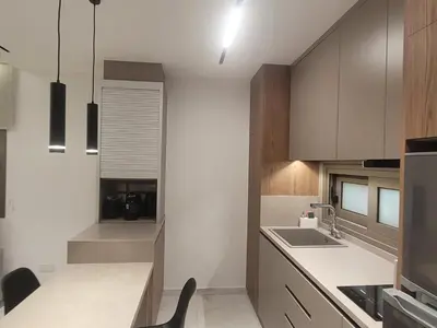 a kitchen with white counters and wooden cabinets at IOLENA Seaview Apartment in Pyla