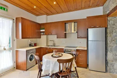 a kitchen with a table and a white refrigerator at Vasilikis House in Kalopanayiotis