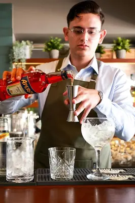 a man pouring a drink into a glass at Mikes Kanarium City Hotel in Larnaka