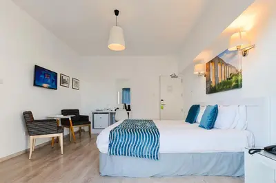 a bedroom with a bed and a desk and a table at Mikes Kanarium City Hotel in Larnaka