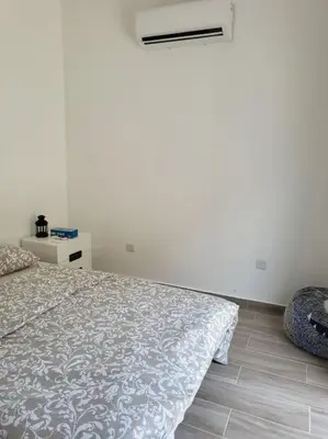 a white bedroom with a bed and a night stand at Limassol mountain and sea views in Limassol