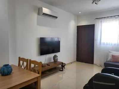 a living room with a table and a tv on the wall at Limassol mountain and sea views in Limassol