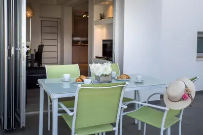 a table with green chairs and a hat on it at Villa Nora in Protaras