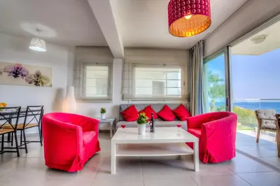 a living room with red chairs and a table at Beachfront Trident in Protaras