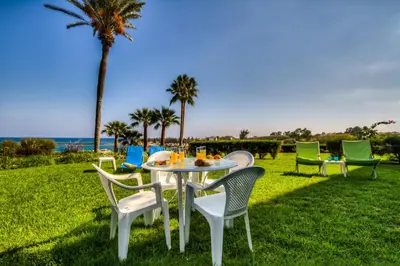 a table and chairs on a lawn with palm trees at Beachfront Trident in Protaras