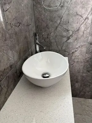 a white sink in a bathroom with a stone wall at Luca Apts Napa in Ayia Napa