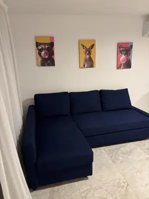 a blue couch in a room with three pictures on the wall at Luca Apts Napa in Ayia Napa
