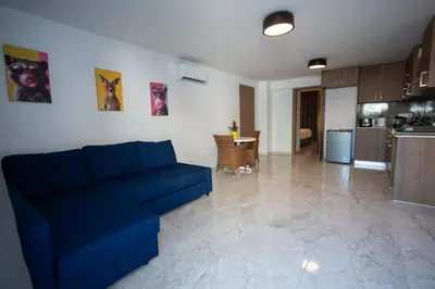 a living room with a blue couch and a kitchen at Luca Apts Napa in Ayia Napa