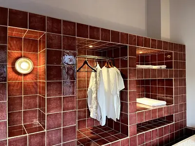 a bathroom with a tiled wall with a mirror at Stin Avli tou Pavlou Guest House in Omodos