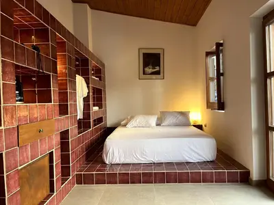a bedroom with a bed and a tiled wall at Stin Avli tou Pavlou Guest House in Omodos