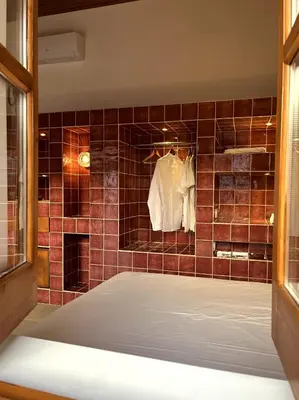 a bathroom with a tiled shower with a robe at Stin Avli tou Pavlou Guest House in Omodos
