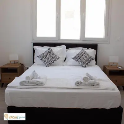 a bed with towels on it with two windows at Villa Orash in Larnaka