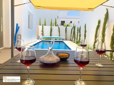 three glasses of wine sitting on a table next to a pool at Villa Orash in Larnaka