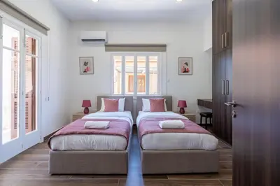 two beds in a room with two windows at Aura 2-Bedroom Apartment in Larnaca in Larnaka