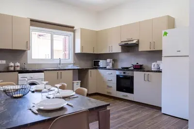 a kitchen with a table and a white refrigerator at Aura 2-Bedroom Apartment in Larnaca in Larnaka