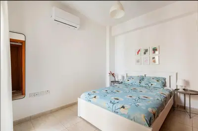 a white bedroom with a bed and a table at Top Floor Apartment City Center in Larnaka