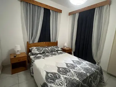 a bedroom with a black and white bed and windows at Guest House in Larnaka