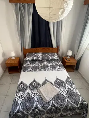 a bedroom with a bed with a black and white comforter at Guest House in Larnaka