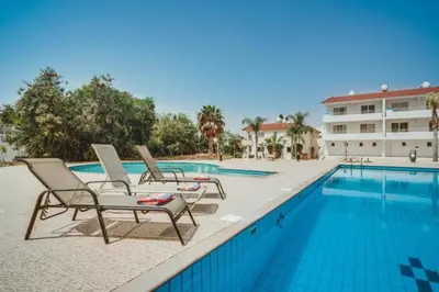 a swimming pool with two lounge chairs next to a building at Hana Nissi in Ayia Napa