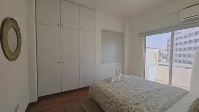 a white bedroom with a bed and a large window at STAY City Life Apartment II in Nicosia