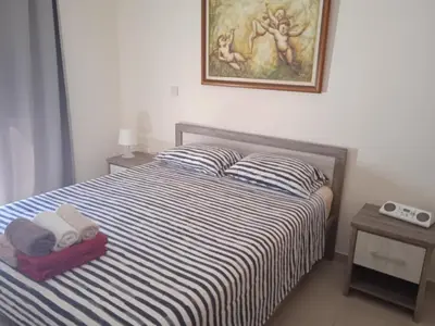 a bedroom with a bed with striped sheets and a picture on the wall at Xylophagou Rest and Relax 4 Top floor Big Balcony 1 bedroom apartment in Xylophaghou