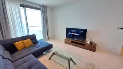 a living room with a blue couch and a television at Del Mar 2 Bedroom Deluxe Seaside 'A' Residence in Limassol