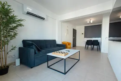 a living room with a blue couch and a table at Maestro Sunrise View in Larnaka