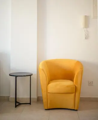 a yellow chair and a table in a room at Maestro Sunrise View in Larnaka