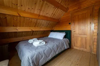 a bed in a wooden cabin with towels on it at Ktima To Alliotiko - Lofou 1 in Lofou