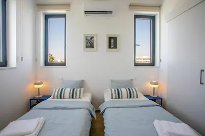 two beds in a room with three windows at Palmove Newly Build Seaview Apt in Larnaka
