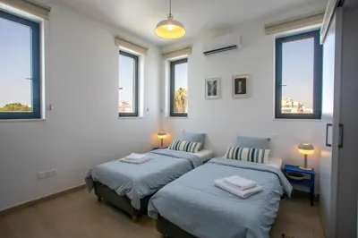 two beds in a white room with windows at Palmove Newly Build Seaview Apt in Larnaka