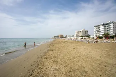 a beach with people standing in the water and buildings at Palmove Newly Build Seaview Apt in Larnaka